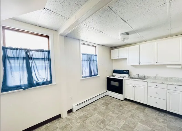 a kitchen with granite countertop a stove a sink and a refrigerator