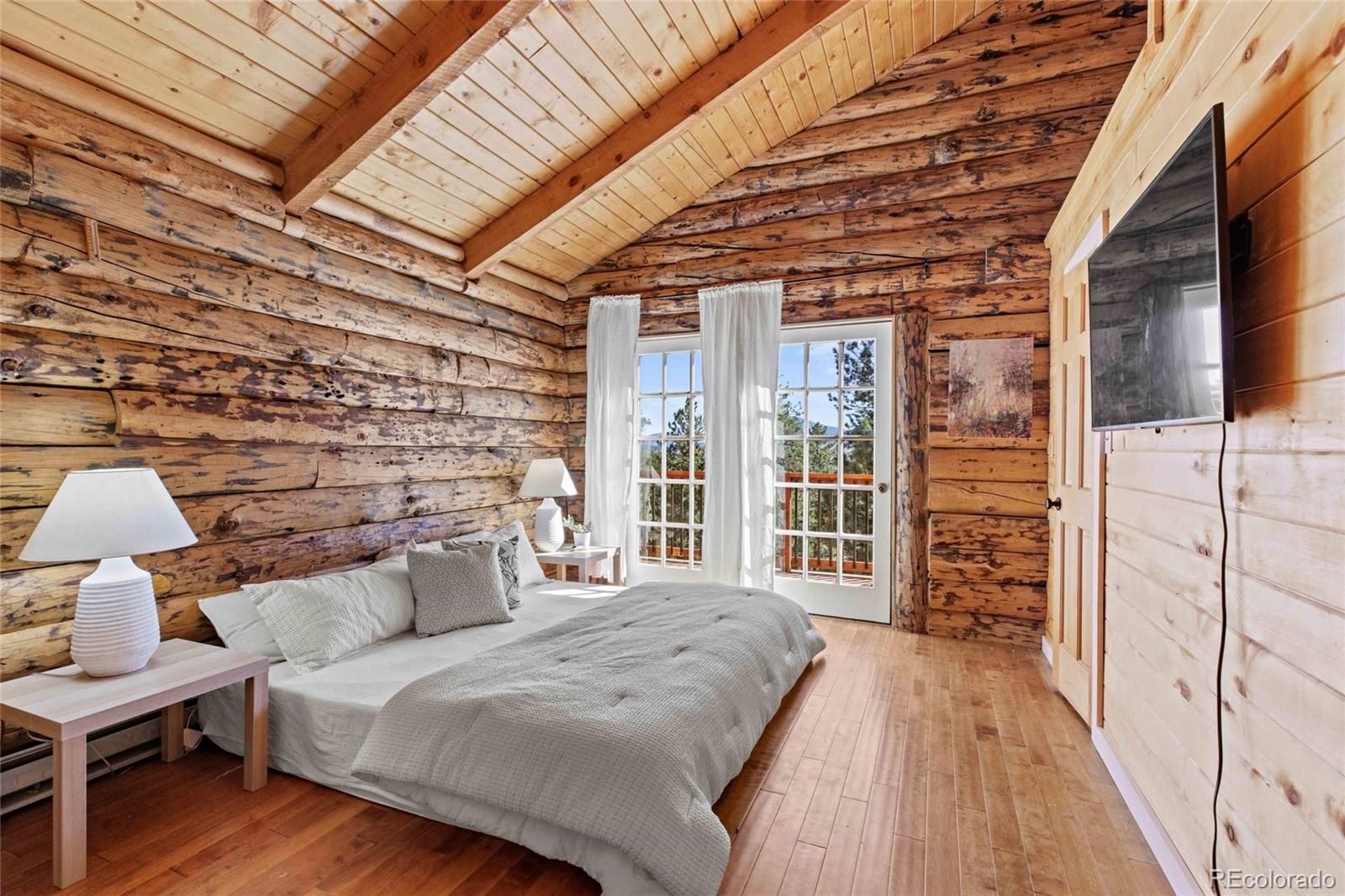 310 Holmes Gulch Road Bailey, CO 80421 - Photo 14 of 48 a spacious bedroom with a bed and wooden floor