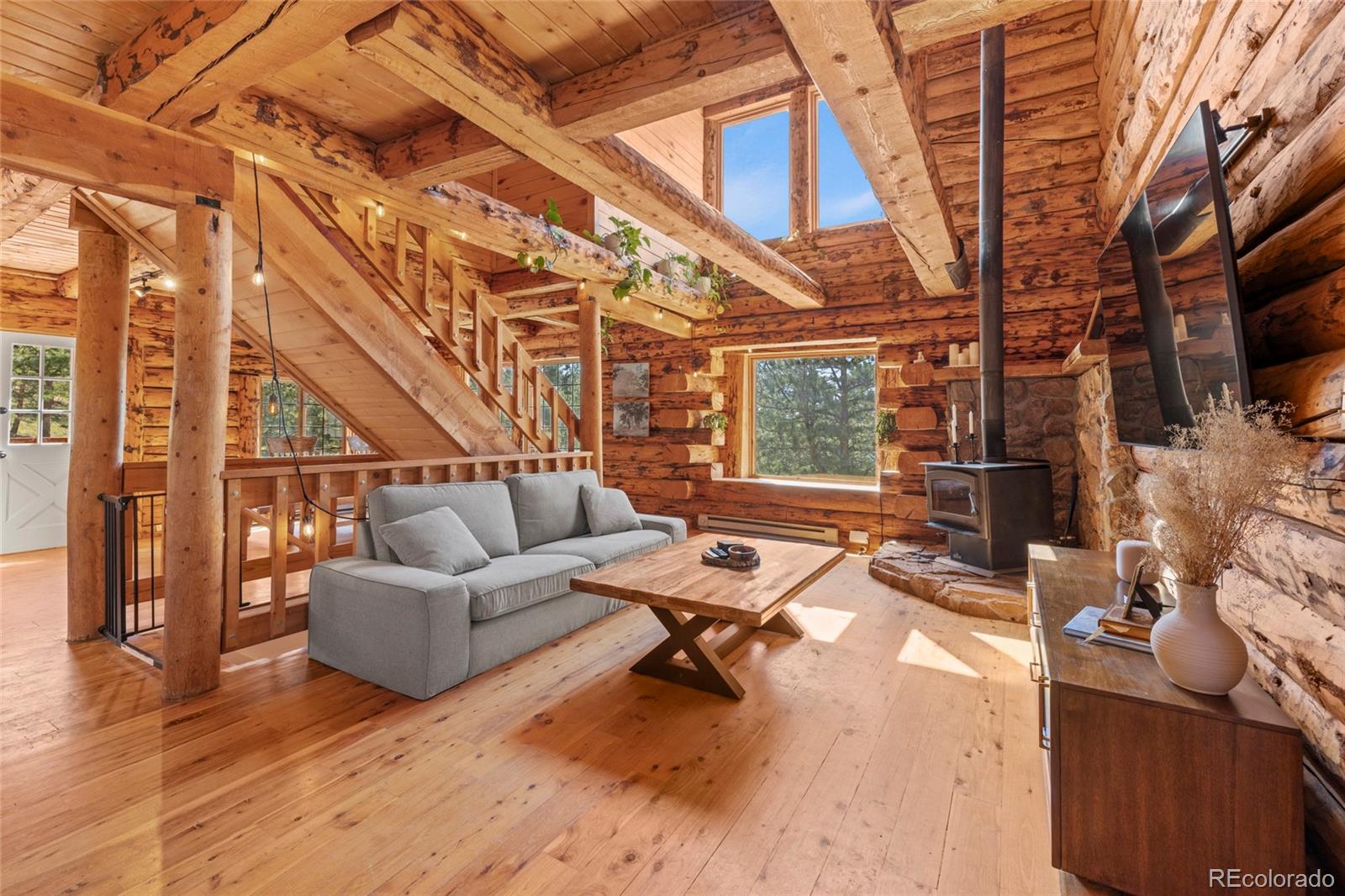 310 Holmes Gulch Road Bailey, CO 80421 - Photo 2 of 48 a living room with fireplace furniture and a floor to ceiling window