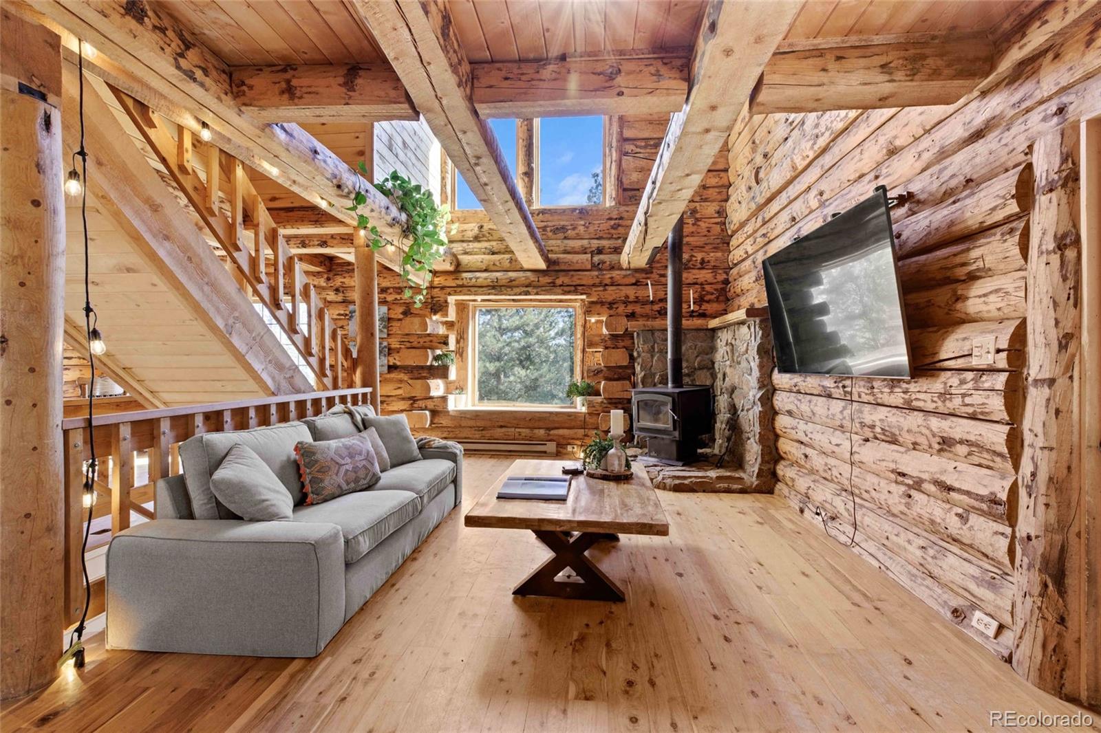 310 Holmes Gulch Road Bailey, CO 80421 - Photo 5 of 48 a living room with furniture a fireplace and a flat screen tv
