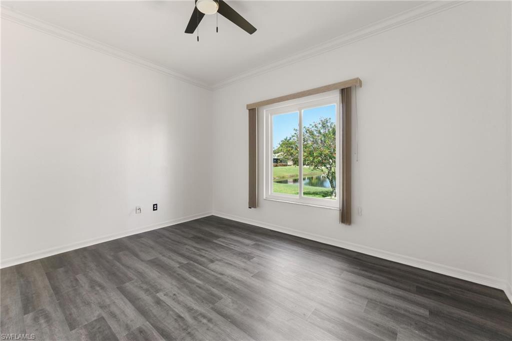 223 Stanhope Circle Naples, FL 34104 - Photo 18 of 41 Bright interior space featuring a window with a water feature, wood-finish flooring, a ceiling fan, crown molding, and white baseboards