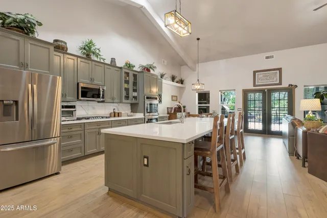 a kitchen with stainless steel appliances a stove a sink dishwasher a refrigerator and a dining table with wooden floor