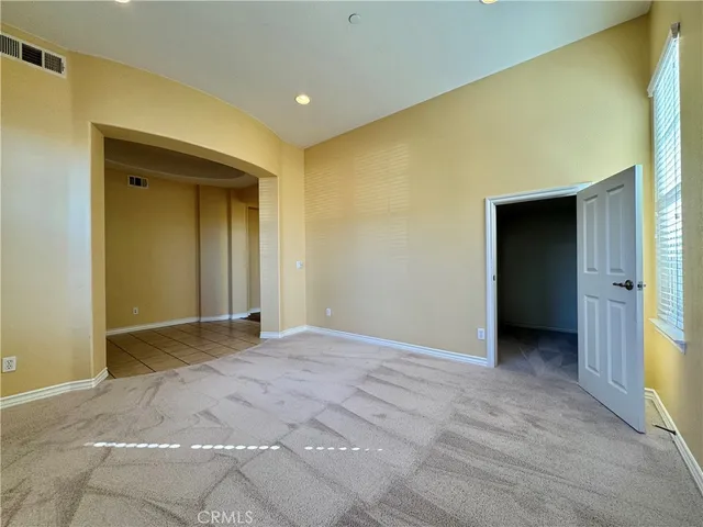 a view of an empty room with closet and entryway