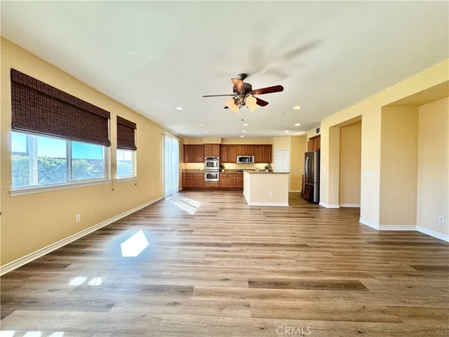 a kitchen with stainless steel appliances granite countertop a stove a sink a refrigerator and white cabinets with wooden floor