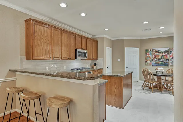 a kitchen with stainless steel appliances granite countertop a table and chairs in it