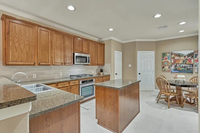 a kitchen with stainless steel appliances granite countertop a stove a sink a microwave a dining table and chairs