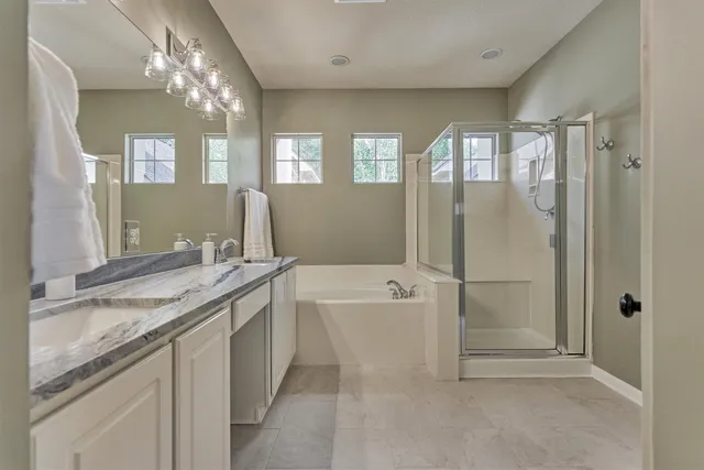 a spacious bathroom with a granite countertop tub sink shower and mirror