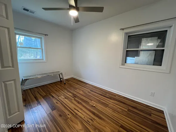 an empty room with wooden floor cabinet and windows