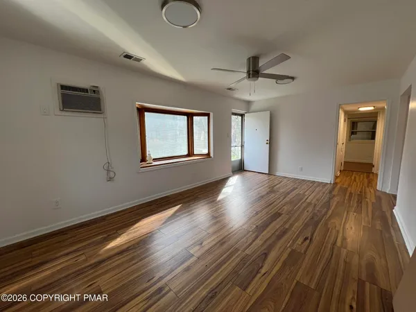 a view of an empty room with wooden floor and a window