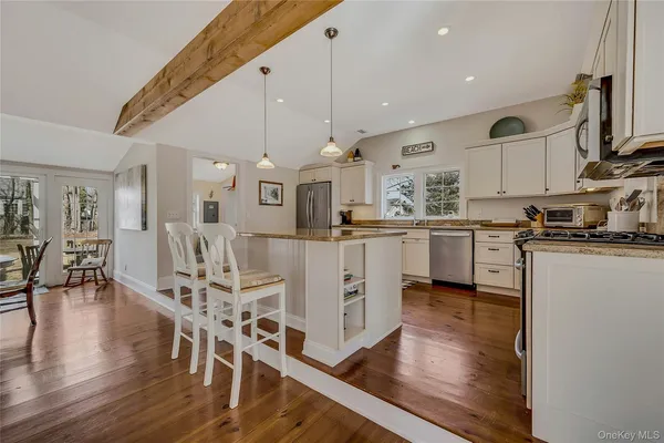 a kitchen with stainless steel appliances kitchen island granite countertop a stove a sink a refrigerator and a dining table with wooden floor