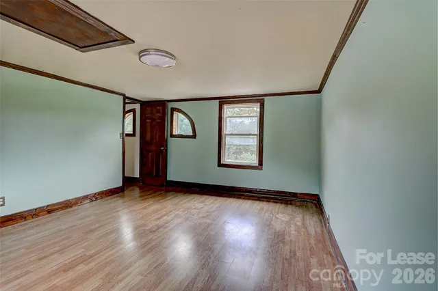 a view of an empty room with window and wooden floor