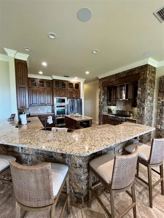 a kitchen with stainless steel appliances granite countertop a stove a sink a counter space and chairs