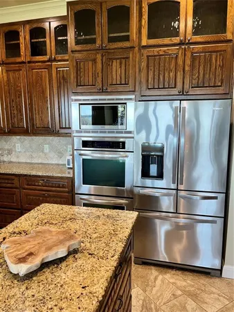 a kitchen with stainless steel appliances granite countertop a refrigerator and a stove top oven