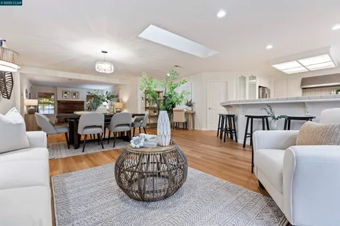 a living room with furniture a rug and a dining table