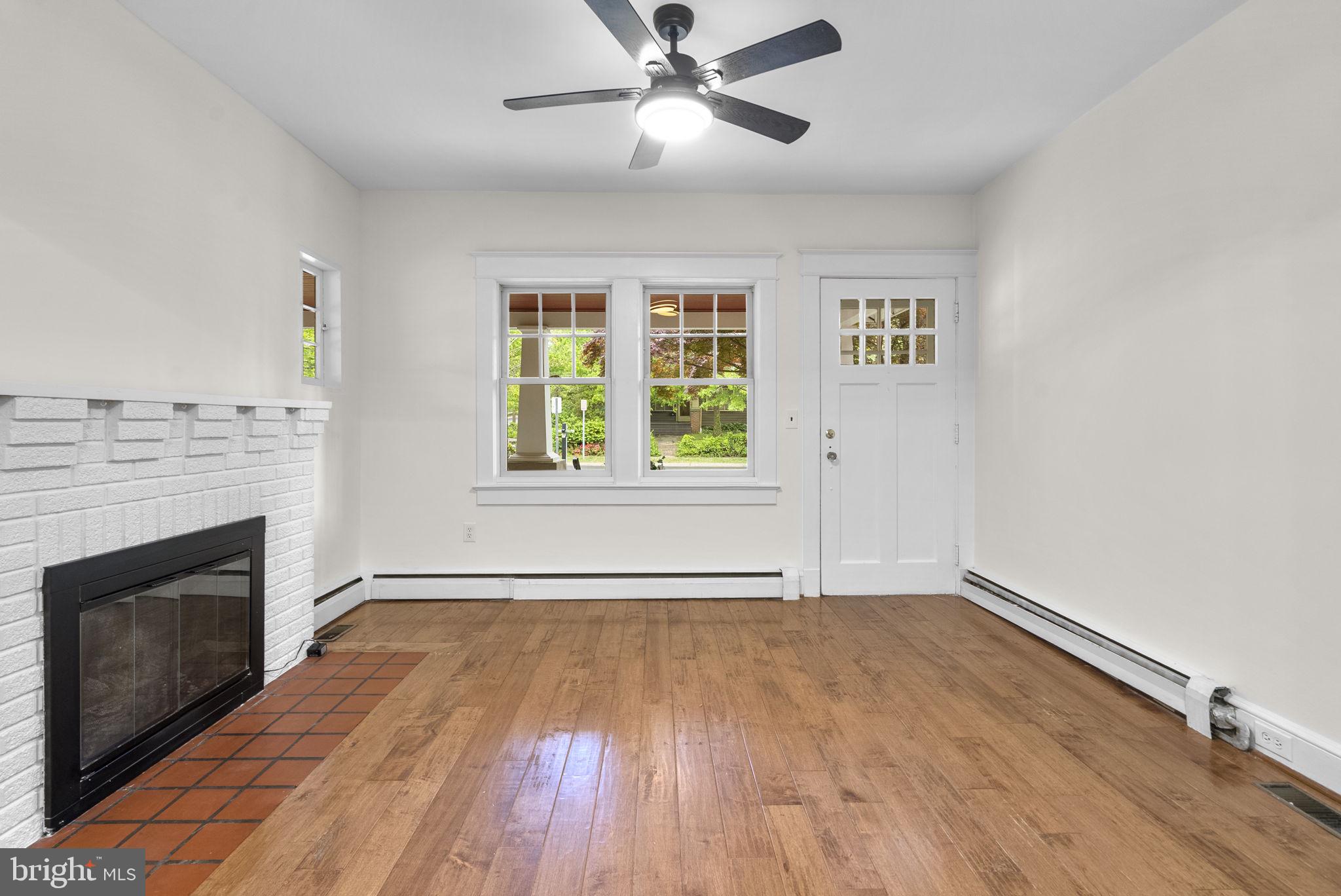 9120 Glenridge Road Silver Spring, MD 20910 - Photo 6 of 59 an empty room with wooden floor a ceiling fan a fireplace and windows