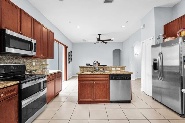 a kitchen with stainless steel appliances granite countertop a stove top oven a sink and a refrigerator