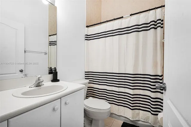 a bathroom with a sink a toilet a mirror and shower curtain