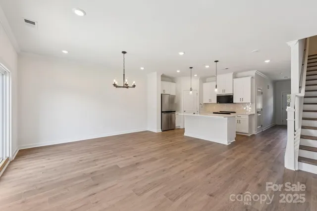 a large kitchen with kitchen island a stove a sink dishwasher and a refrigerator with wooden floor