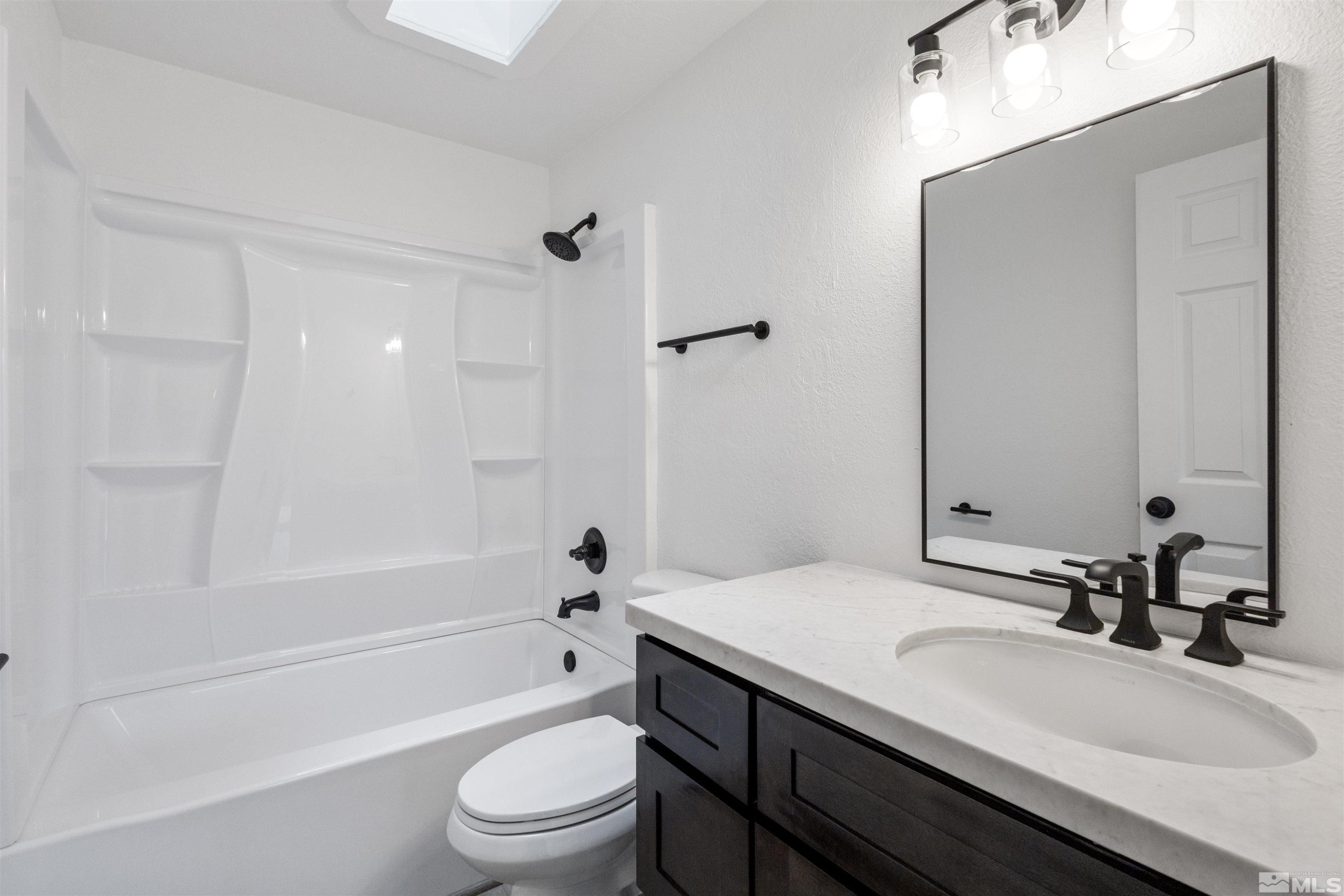 6798 Flower Street Reno, NV 89506 - Photo 11 of 22 a bathroom with a bathtub shower sink vanity mirror and toilet