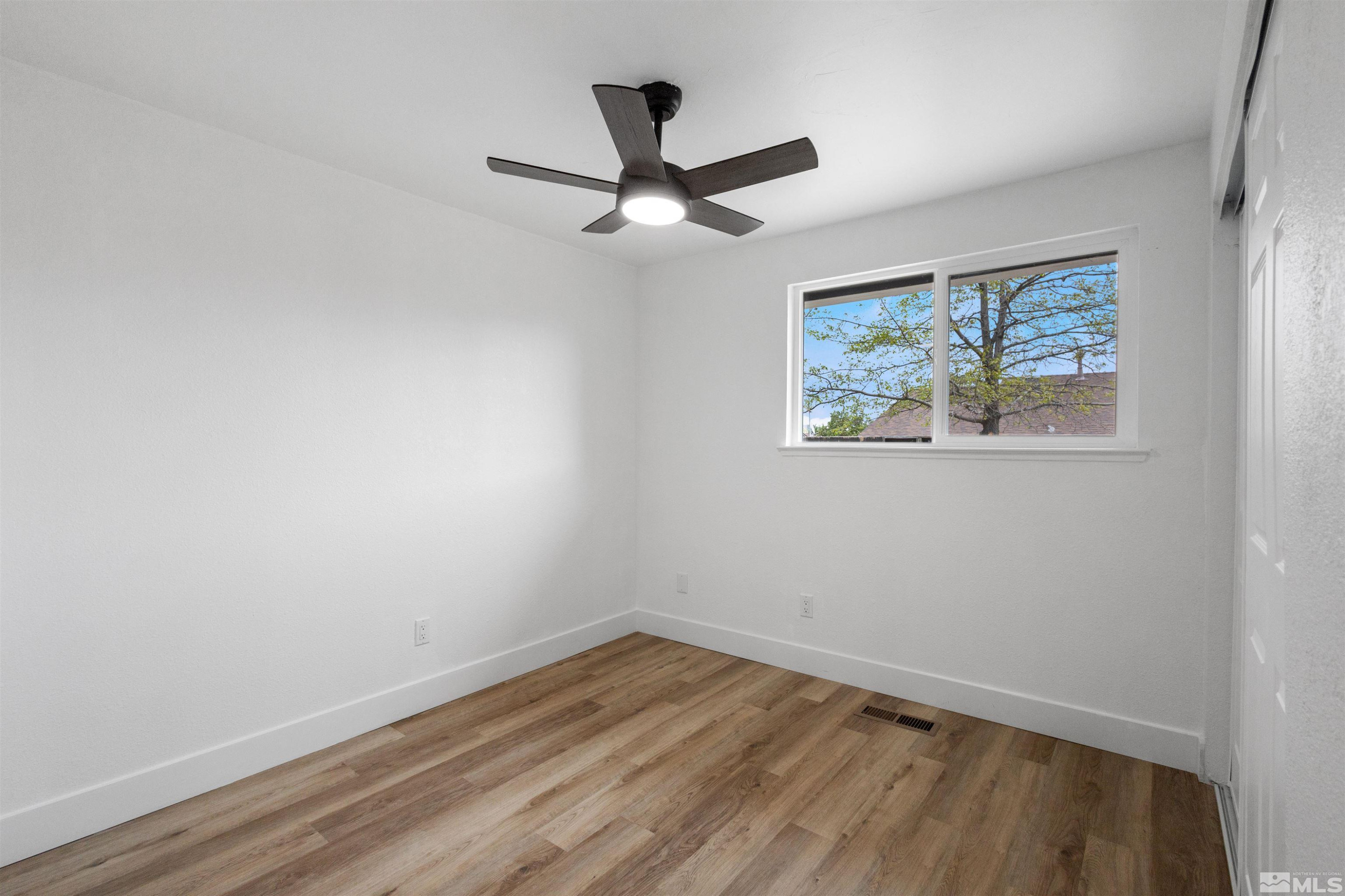 6798 Flower Street Reno, NV 89506 - Photo 13 of 22 an empty room with wooden floor ceiling fan and windows