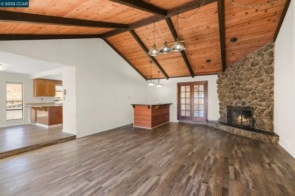 a view of an empty room with wooden floor and a fireplace