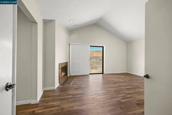 a view of an empty room with a fireplace and a window