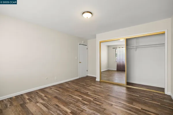 a view of an empty room with wooden floor and cabinets