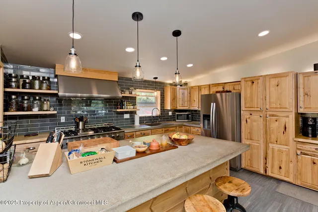 a kitchen with stainless steel appliances granite countertop a sink a refrigerator and a stove