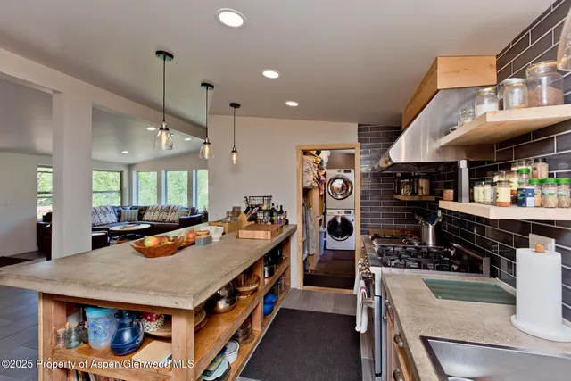 a large kitchen with stainless steel appliances a stove center island a refrigerator and a view of living room