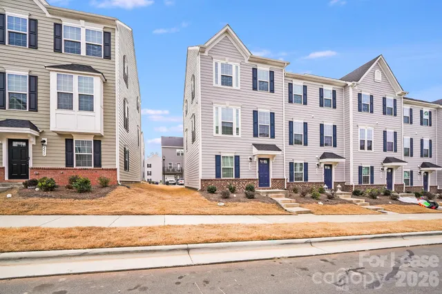 a front view of a building with lot of cars and trees