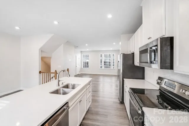 a kitchen with stainless steel appliances kitchen island granite countertop a sink and dishwasher a stove top oven with wooden floor