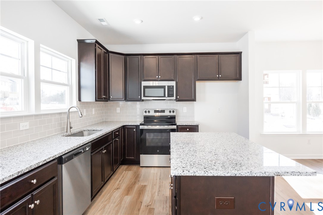 a kitchen with stainless steel appliances granite countertop a sink stove and microwave