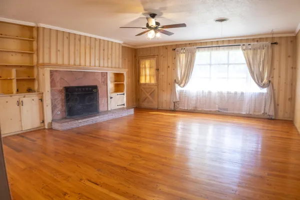 a view of a livingroom with a fireplace a ceiling fan and windows