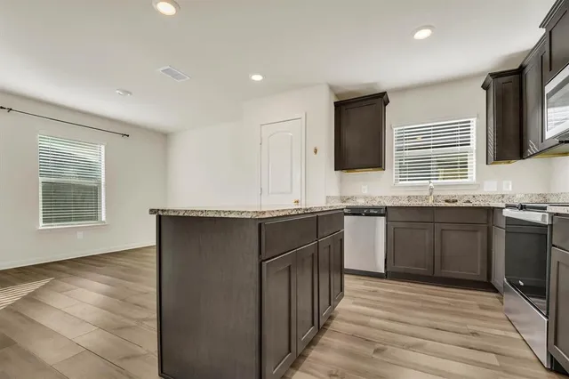 a kitchen with granite countertop a sink cabinets and stainless steel appliances