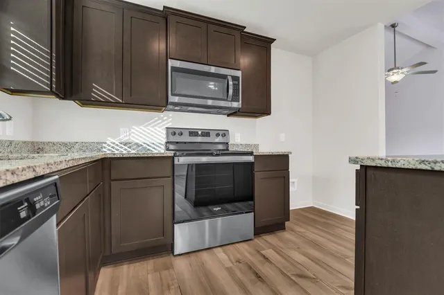 a kitchen with granite countertop a stove and a microwave with cabinets