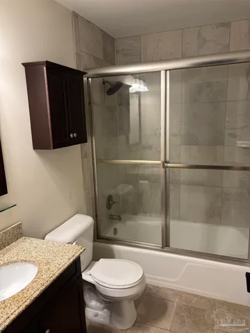 a bathroom with a granite countertop bathtub shower and toilet