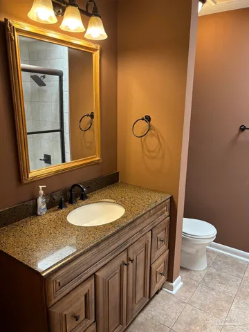 a bathroom with a granite countertop toilet sink and mirror