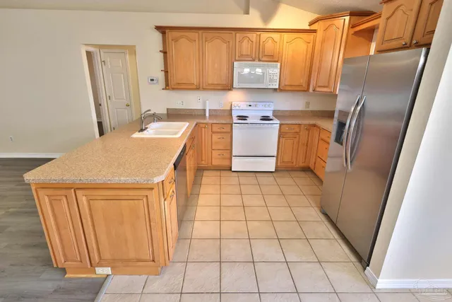 a kitchen with stainless steel appliances a sink a stove a refrigerator a microwave and cabinets