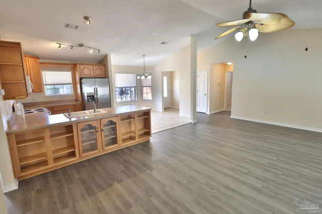 a large kitchen with stainless steel appliances a large counter top a chandelier and living room view