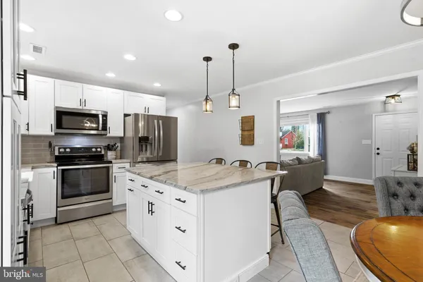 a kitchen with stainless steel appliances a stove a sink a refrigerator a microwave oven a stove a dining table and chairs