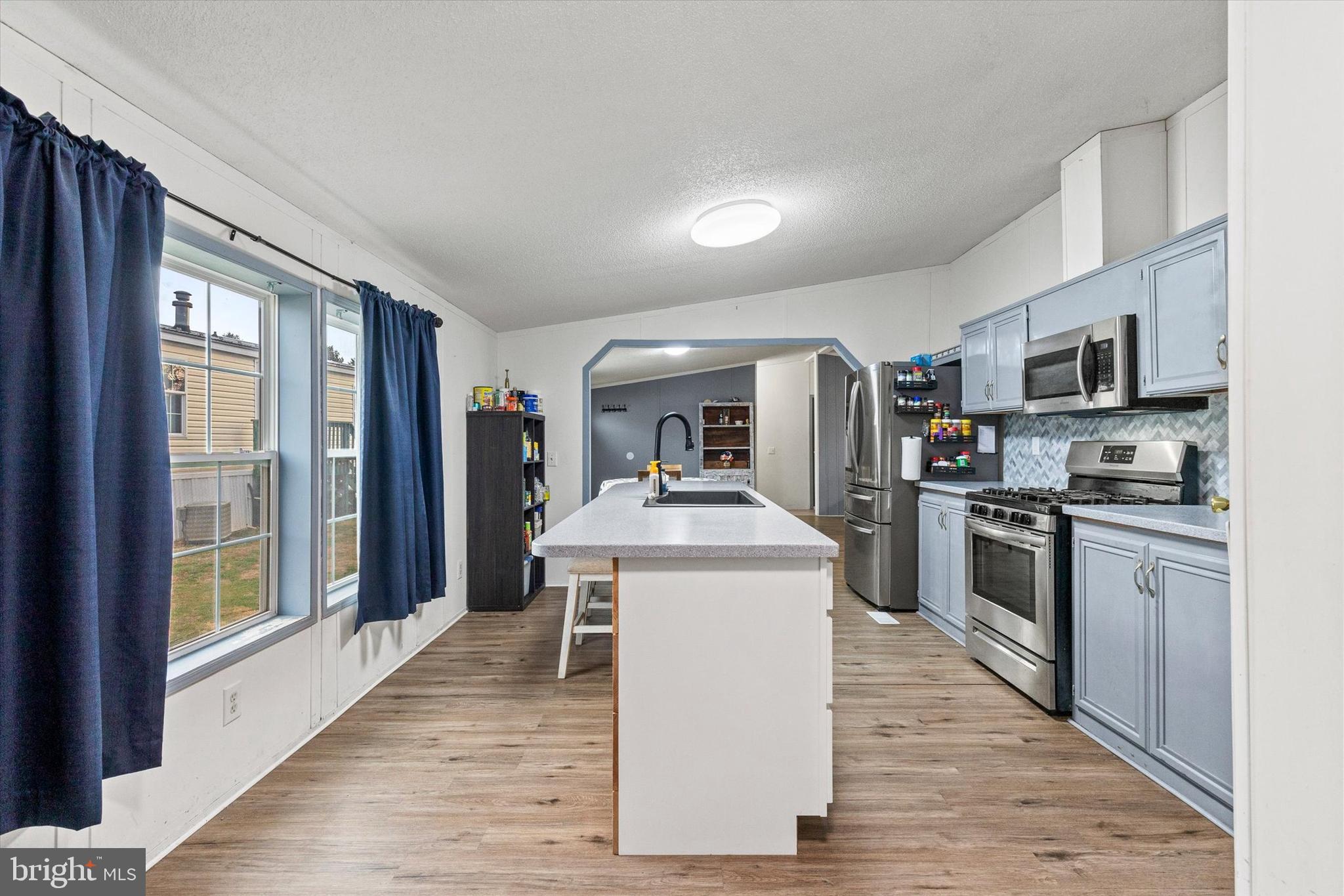 14 Junction Road Millersburg, PA 17061 - Photo 10 of 23 a kitchen with kitchen island granite countertop a stove top oven a sink dishwasher a refrigerator and a dining table with wooden floor