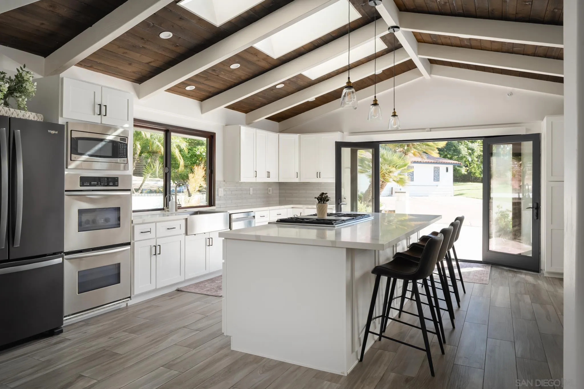 15102 Sun Valley Lane Del Mar, CA 92014 - Photo 8 of 45 a kitchen with stainless steel appliances granite countertop a stove a refrigerator a microwave oven with a dining table and chairs with wooden floor