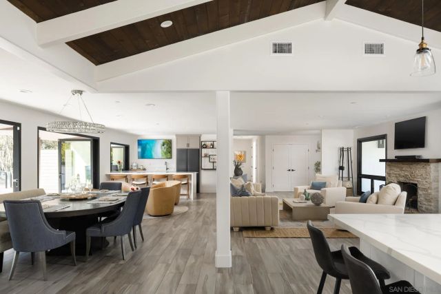 a living room with stainless steel appliances furniture a fireplace and a open kitchen view