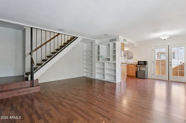a view of empty room with wooden floor and stairs