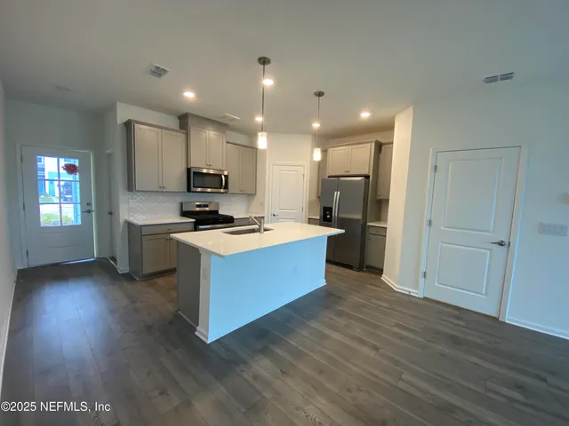 a large kitchen with stainless steel appliances granite countertop a large counter top a sink and a refrigerator