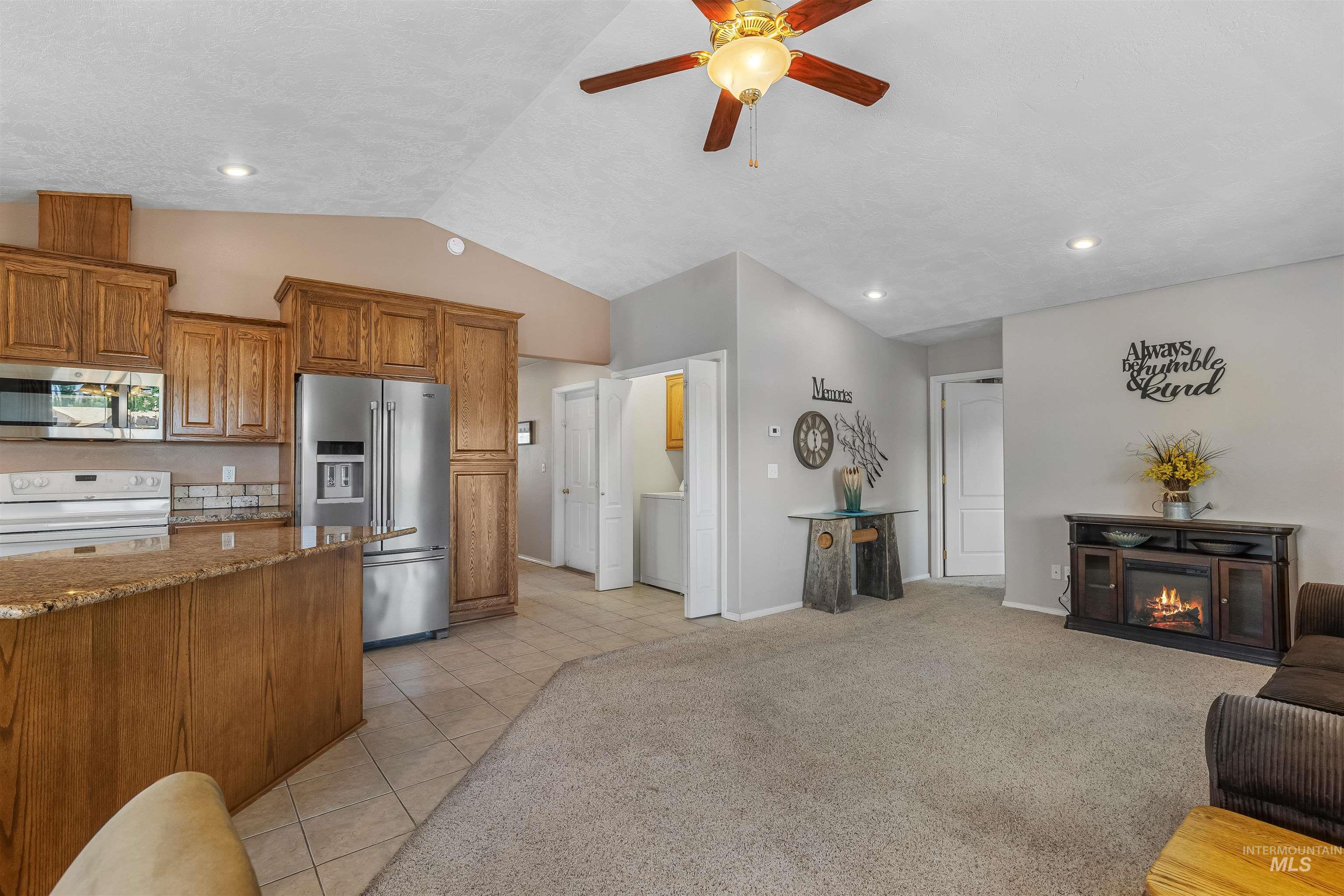 935 Grelle Avenue Lewiston, ID 83501 - Photo 19 of 33 Kitchen with stainless steel appliances, brown cabinets, vaulted ceiling, a ceiling fan, and a glass covered fireplace