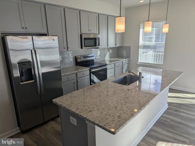 a kitchen with stainless steel appliances granite countertop a sink refrigerator and microwave