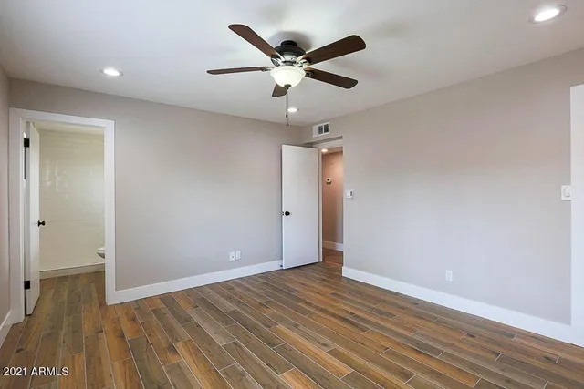an empty room with wooden floor and ceiling fan