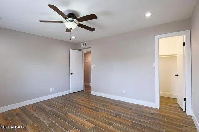 an empty room with wooden floor and ceiling fan