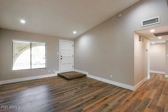 a view of an empty room with wooden floor and a window